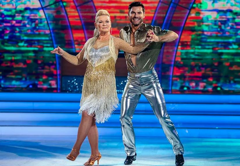 Shuigh Eileen ar an deasc, chas sí a cosa anonn agus chuaigh sí síos chuig a páirtí rince, Robert, ar an urlár 