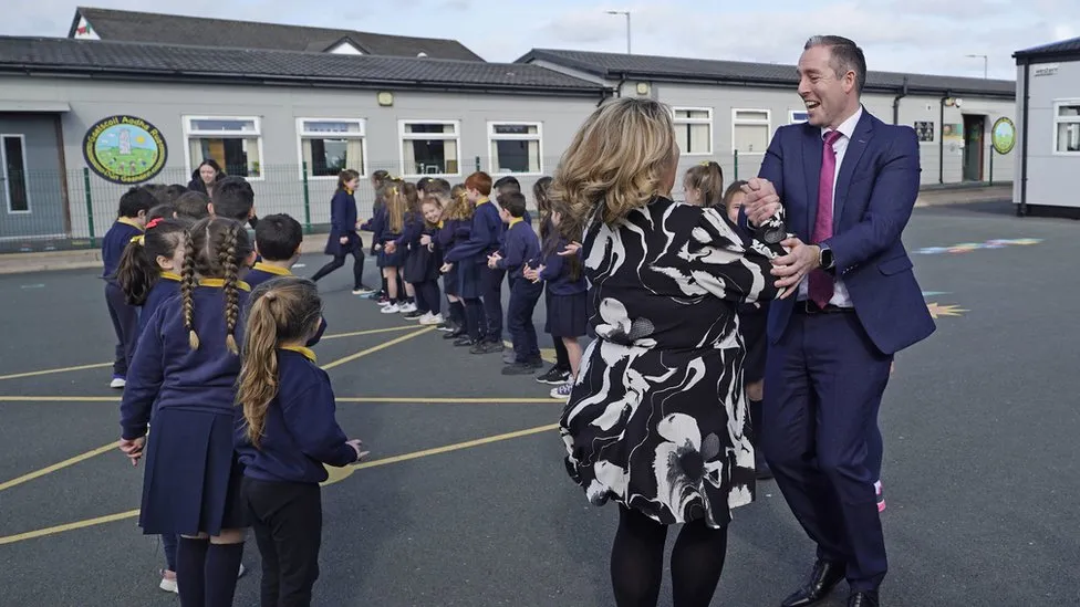 Paul Given ón DUP ag damhsa leis an príomhoide, Móna Uí Dhochartaigh