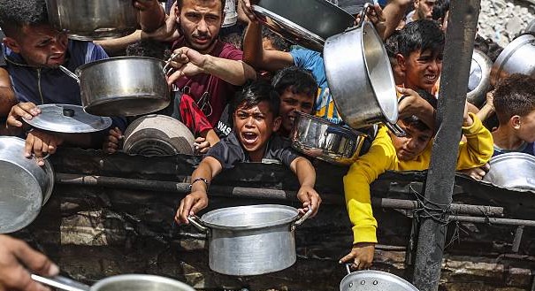 Palaistínigh ag streachailt leis an ocras in Gaza de bharr trádbhac Iosrael(Pictiúr le Mahmoud Issa/Anadolu via Getty Images)