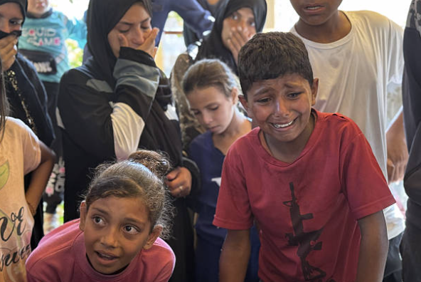 Gaolta beirt Palaistíneach a maraíodh in ionsaithe Iosraelacha, ag caoineadh agus na coirp á dtabhairt chuig Ospidéal Nasser i Khan Yunis, Gaza ar an 10 Samhain 2025