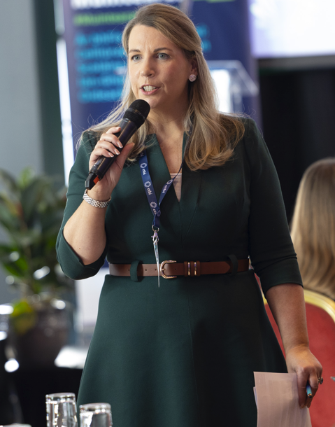 Gean Gilger, comh-ordaitheoir Muintearas ’26, ag labhairt leis an lucht freastail.
