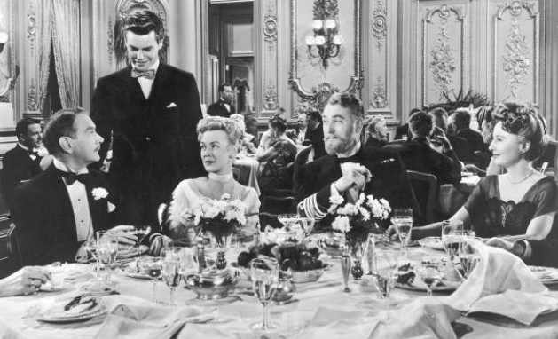 Ó chlé go deas, Clifton Webb, Robert Wagner, Frances Bergen, Brian Aherne agus Barbara Stanwyck ag caint thar dhinnéar i radharc ón scannán Titanic, 1953. Pic: 20th Century Fox/Archive Photos/Getty Images
